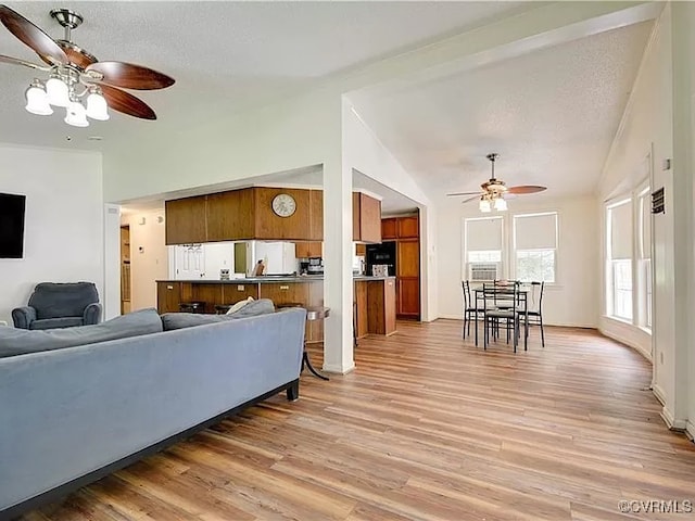 living area with a textured ceiling, light wood-type flooring, lofted ceiling, and ceiling fan