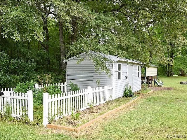 view of home's exterior with a lawn, an outdoor structure, and fence