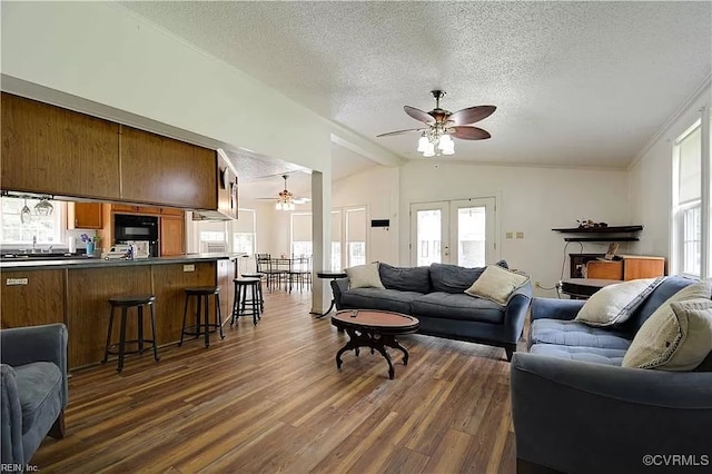 living area featuring a textured ceiling, dark wood-style floors, a ceiling fan, and vaulted ceiling