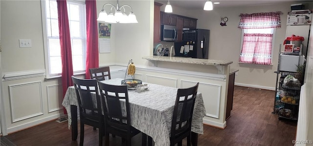 dining area featuring dark wood-style floors and an inviting chandelier