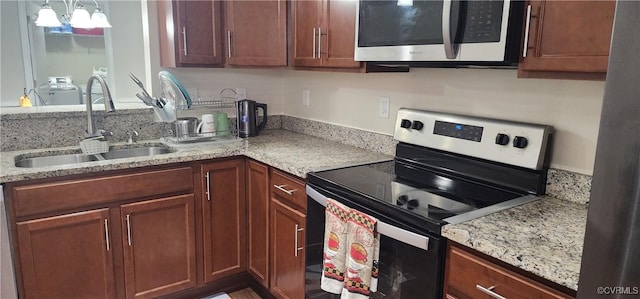 kitchen featuring light stone countertops, appliances with stainless steel finishes, washer / clothes dryer, and a sink