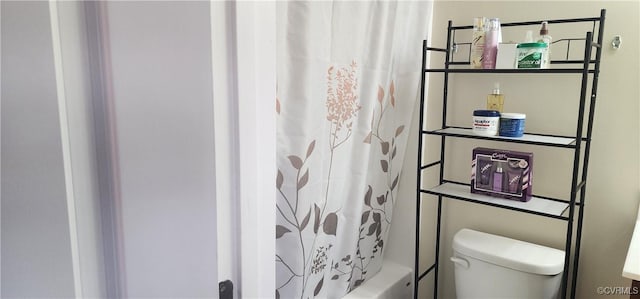 bathroom featuring toilet and shower / bath combination with curtain