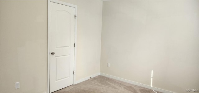 unfurnished room with baseboards and light colored carpet