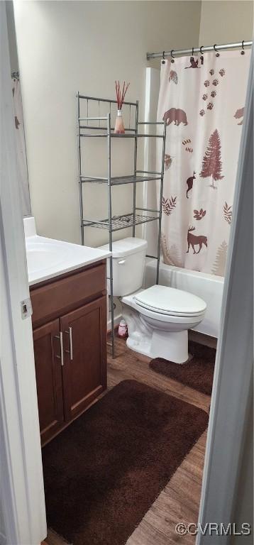 full bath with shower / tub combo, toilet, wood finished floors, carpet, and vanity