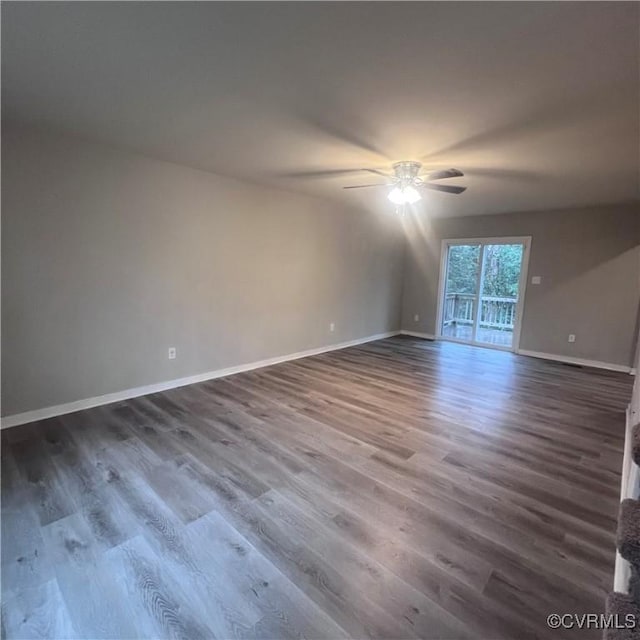 empty room with a ceiling fan, baseboards, and dark wood-type flooring