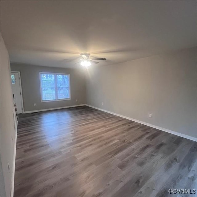 unfurnished room featuring dark wood-type flooring, ceiling fan, and baseboards