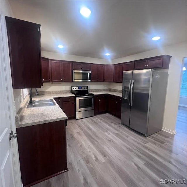 kitchen with recessed lighting, stainless steel appliances, a sink, light wood-style floors, and light countertops