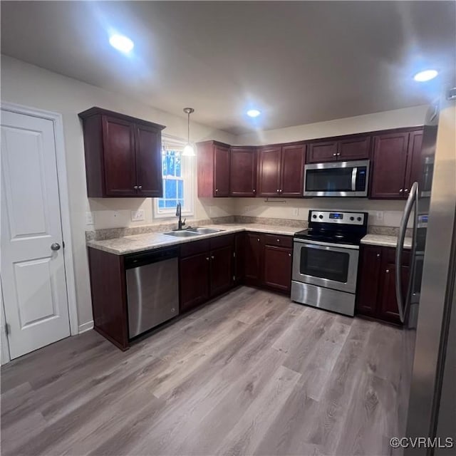 kitchen featuring stainless steel appliances, light countertops, decorative light fixtures, and a sink