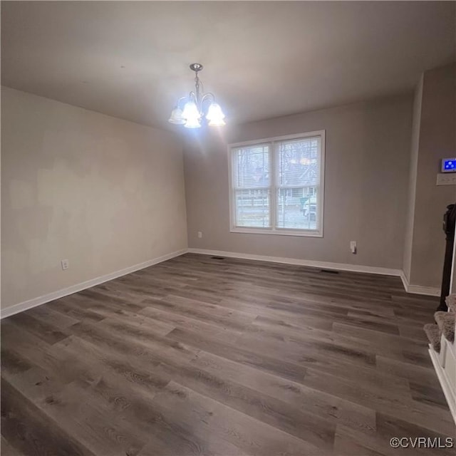 unfurnished dining area with an inviting chandelier, baseboards, and dark wood finished floors