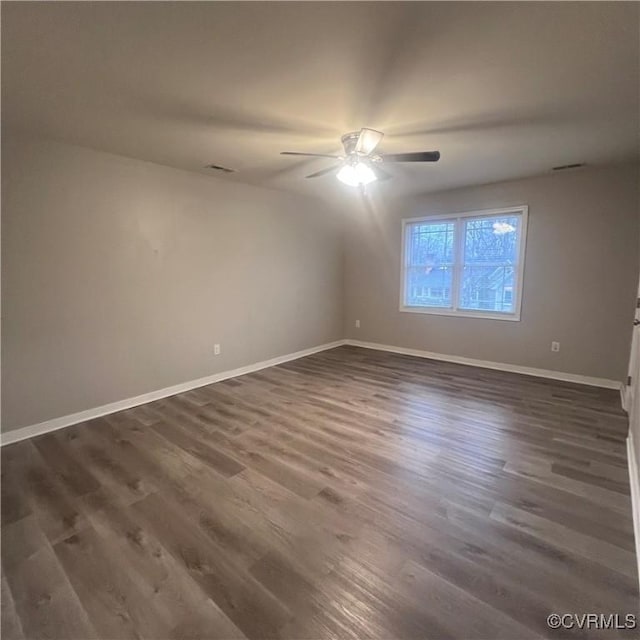 spare room featuring dark wood finished floors, a ceiling fan, and baseboards