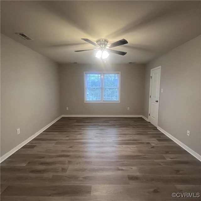 empty room with ceiling fan, dark wood-style flooring, visible vents, and baseboards