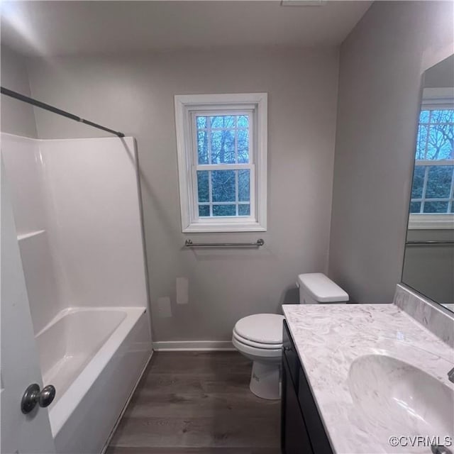 full bathroom with baseboards, toilet, vanity, wood finished floors, and shower / bathtub combination