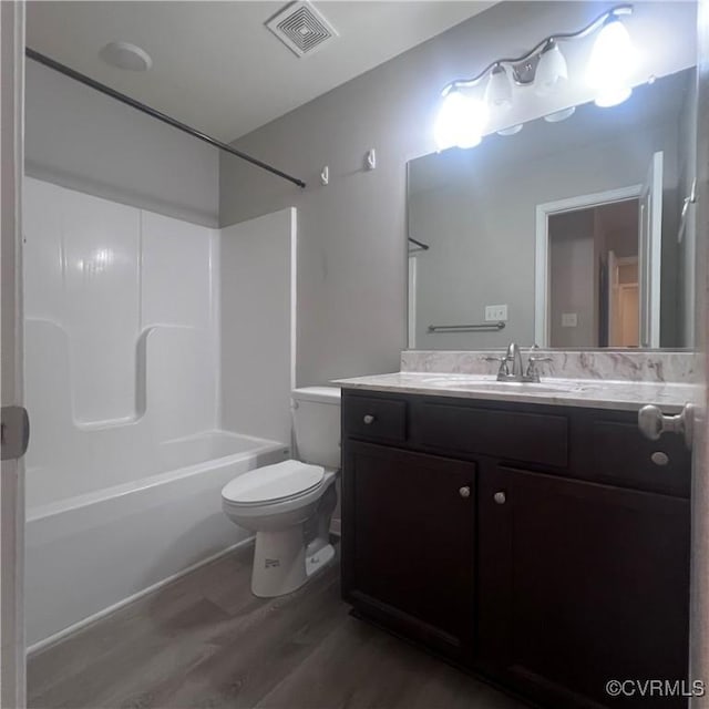 full bathroom with shower / washtub combination, visible vents, toilet, vanity, and wood finished floors