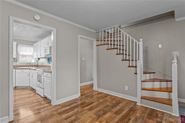 staircase featuring baseboards, ornamental molding, and wood finished floors