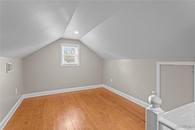 additional living space featuring light wood-style flooring, baseboards, and vaulted ceiling