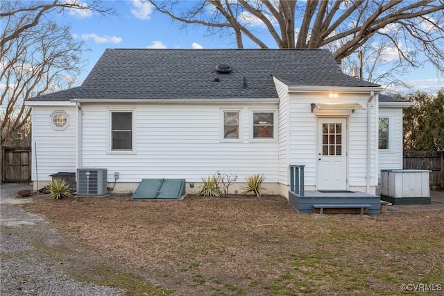 rear view of house featuring central AC unit, roof with shingles, and fence