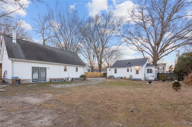 rear view of house featuring a shingled roof and fence