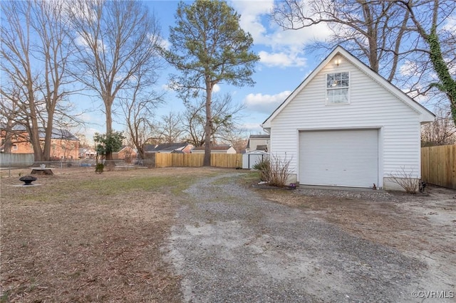 garage with dirt driveway and fence