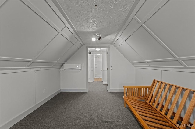 interior space featuring lofted ceiling, dark carpet, a textured ceiling, and baseboards