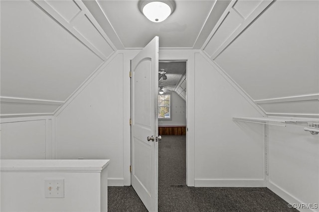 spacious closet featuring lofted ceiling and dark colored carpet