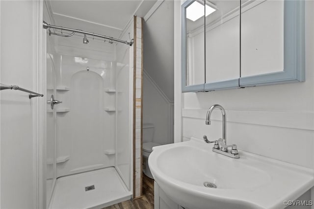 full bathroom with toilet, a stall shower, a sink, and wood finished floors