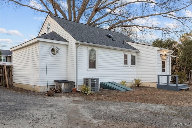 view of side of property with crawl space, cooling unit, and roof with shingles