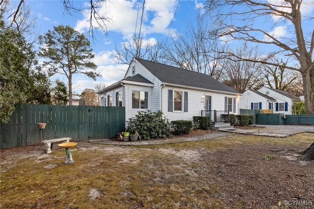 view of home's exterior featuring a shingled roof and fence