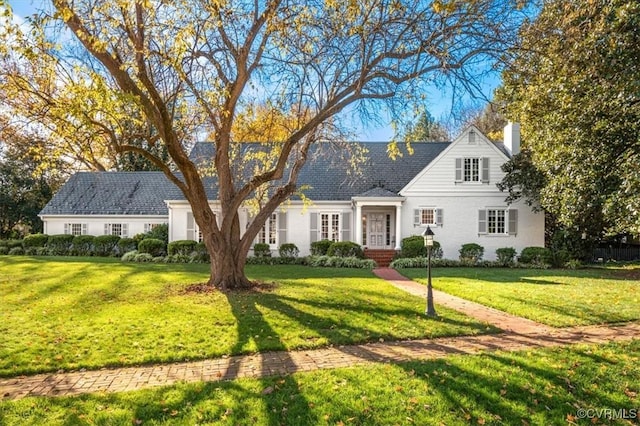 cape cod home featuring a chimney and a front lawn