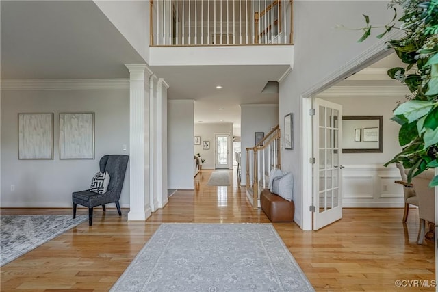 entrance foyer featuring crown molding, decorative columns, stairway, and wood finished floors