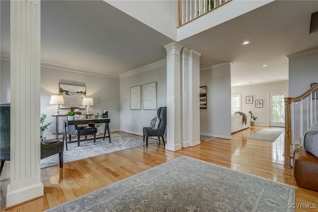 sitting room with wood finished floors, decorative columns, and crown molding