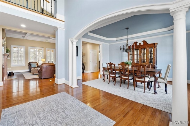 dining room featuring decorative columns, wood finished floors, baseboards, and coffered ceiling