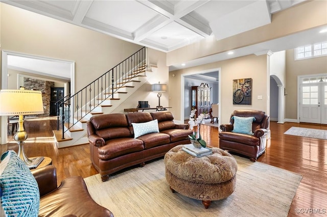 living room featuring arched walkways, coffered ceiling, stairs, and hardwood / wood-style flooring