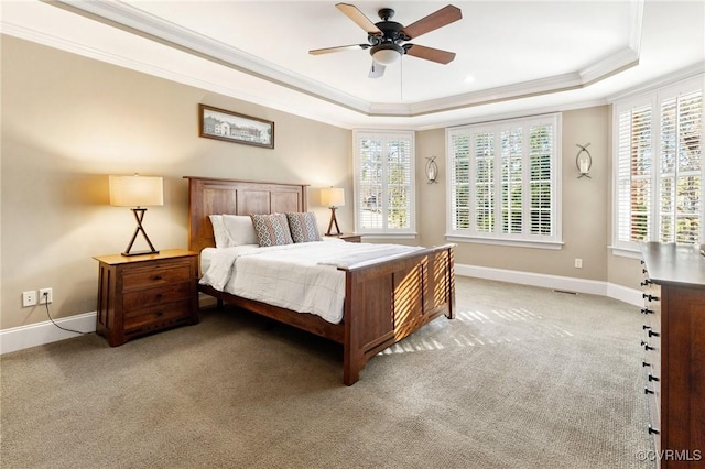 bedroom with ornamental molding, a ceiling fan, a tray ceiling, baseboards, and light colored carpet