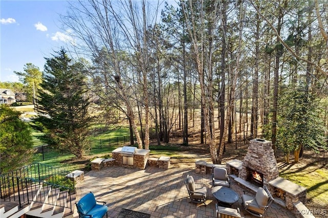 view of patio / terrace featuring an outdoor kitchen, area for grilling, fence, and an outdoor stone fireplace