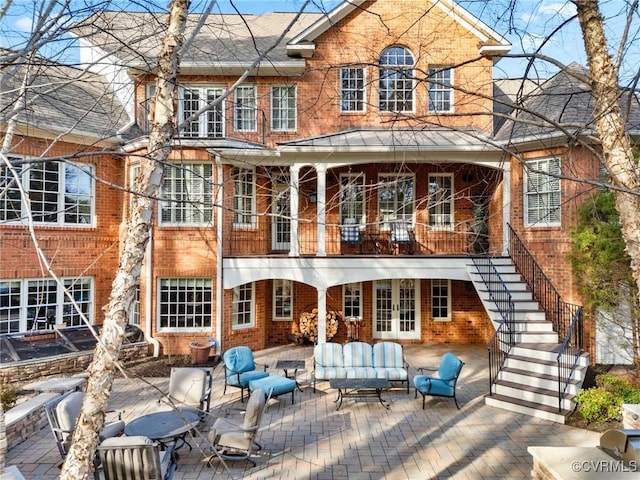 back of property with brick siding, stairs, french doors, outdoor lounge area, and a patio