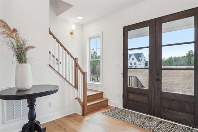 foyer entrance with french doors, stairway, light wood-type flooring, and baseboards