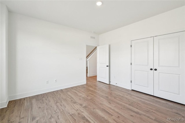 unfurnished bedroom featuring a closet, baseboards, and light wood finished floors