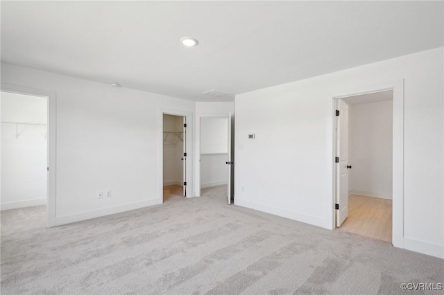 unfurnished bedroom featuring baseboards, a walk in closet, and carpet flooring