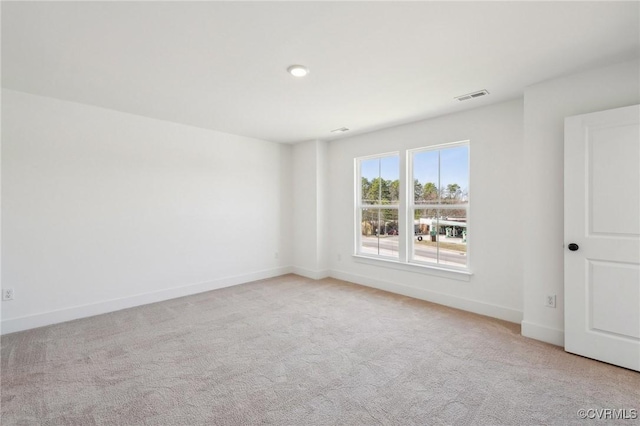 unfurnished room with baseboards, visible vents, and light colored carpet