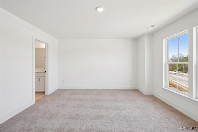 spare room featuring light carpet and baseboards