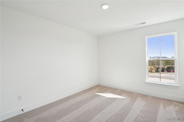 empty room with light colored carpet, visible vents, and baseboards