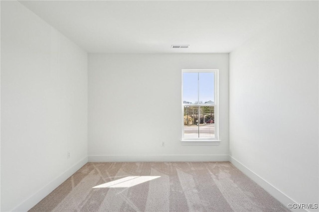 empty room with baseboards, visible vents, and light colored carpet