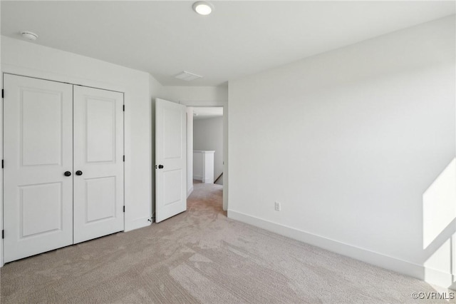 unfurnished bedroom featuring light carpet, a closet, and baseboards