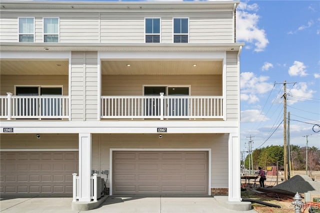 view of front of home featuring a garage, concrete driveway, and a balcony