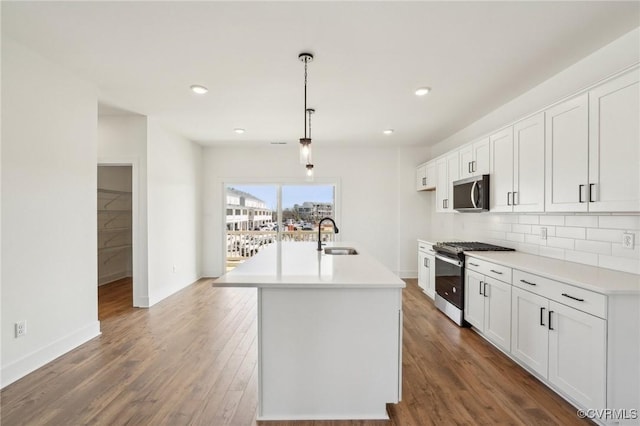 kitchen with dark wood-style floors, stainless steel appliances, decorative backsplash, and light countertops