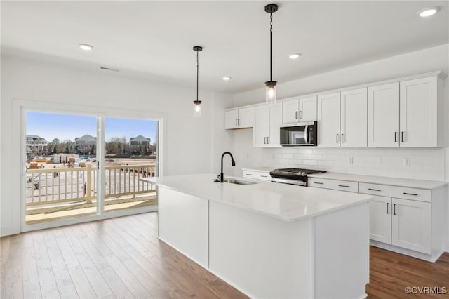 kitchen with tasteful backsplash, light countertops, appliances with stainless steel finishes, a sink, and wood finished floors