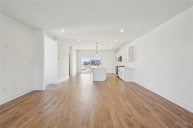 unfurnished living room featuring recessed lighting, a sink, light wood-style flooring, and baseboards