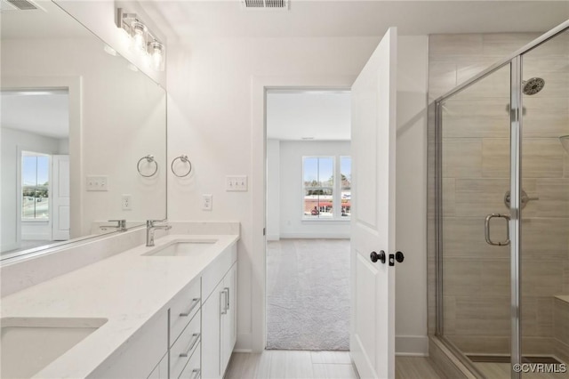 full bathroom featuring double vanity, a shower stall, visible vents, and a sink