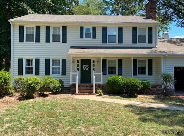 view of front of house with a garage, a chimney, a front lawn, and a porch