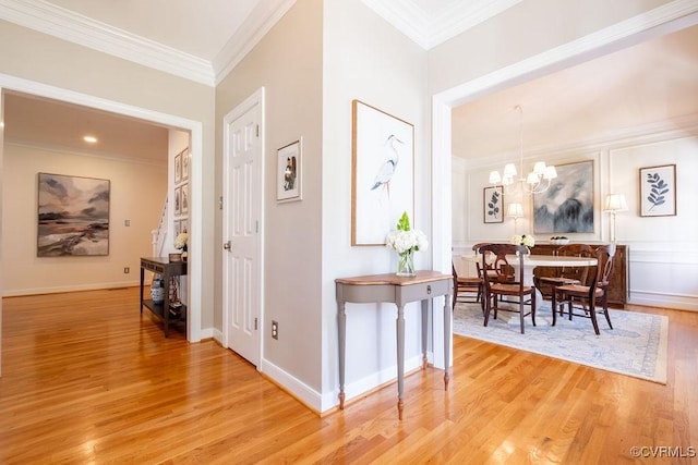 hall featuring baseboards, light wood-style flooring, ornamental molding, and a notable chandelier